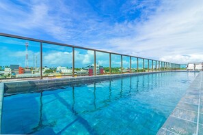 A long, rectangular swimming pool with clear blue water, surrounded by a glass railing. - Porto Prime #308 - Studio Confort by Carpediem (Ipojuca)