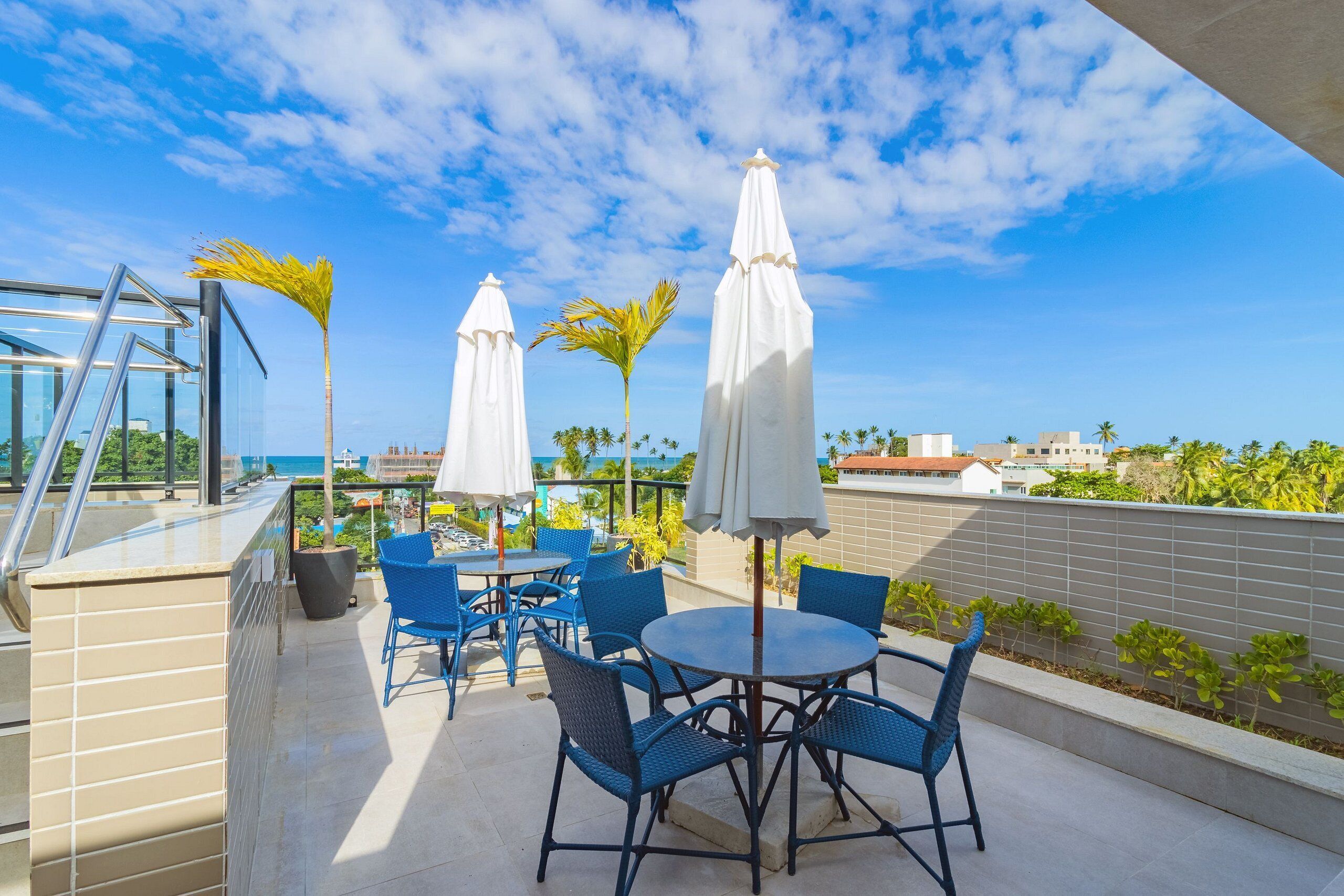Terraza en la azotea con asientos al aire libre, sombrillas y vista al océano.