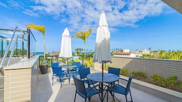 Terraza en la azotea con asientos al aire libre, sombrillas y vista al océano.