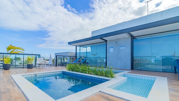 Ein Poolbereich auf dem Dach mit modernem Design, inklusive eines rechteckigen Pools und Sitzbereichen.