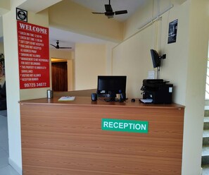 A reception desk with a sign listing check-in and check-out times, a reception number, and a Wi-Fi symbol. - Hotel O RTO Office Krishnarajapura (Bengaluru)