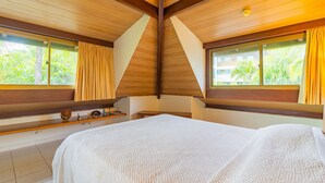 A bedroom with a large bed, wooden ceiling beams, a window with curtains, and a shelf with decorative items. - Beach Class #7113- Bungalow by Carpediem (Ipojuca)