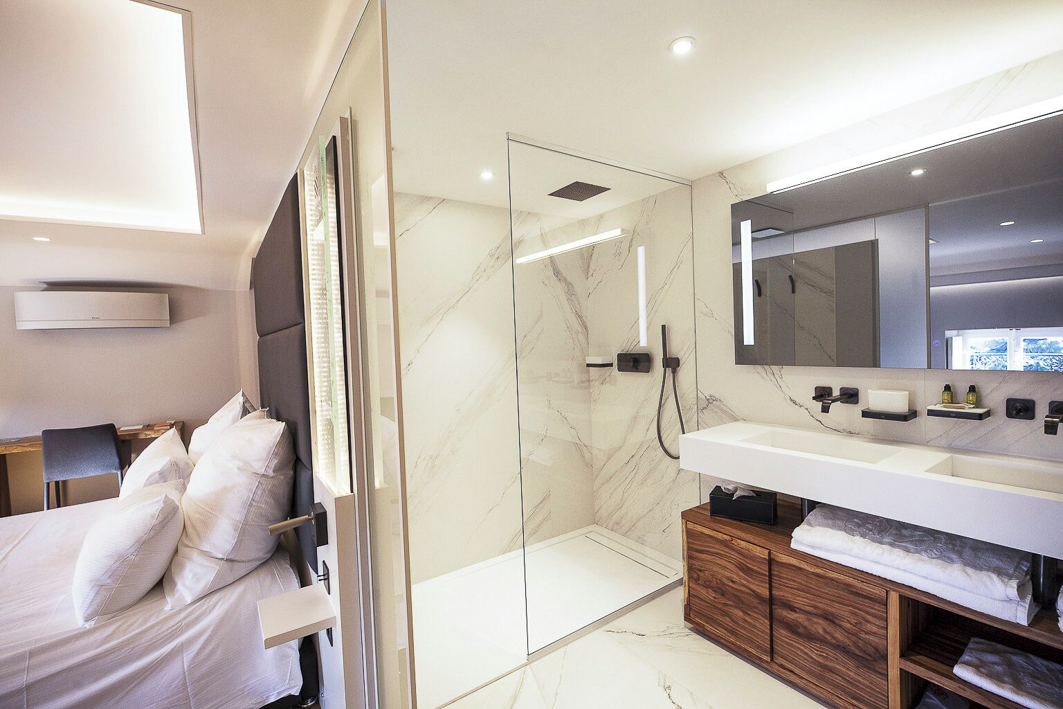 A modern bathroom with a glass-enclosed shower, a large mirror, and a wooden vanity.