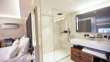A modern bathroom with a glass-enclosed shower, a large mirror, and a wooden vanity.