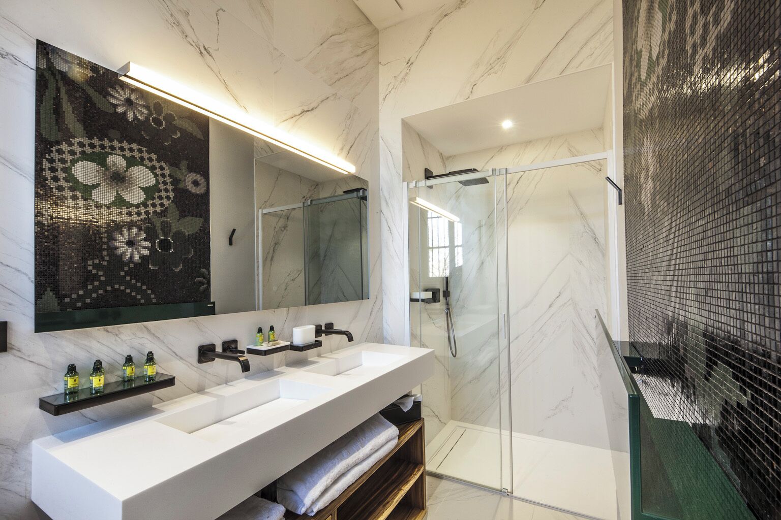 A modern bathroom with a large mirror, two sinks, and a glass-enclosed shower.