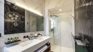 A modern bathroom with a large mirror, two sinks, and a glass-enclosed shower.
