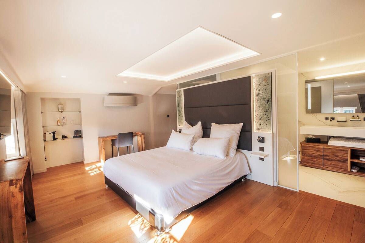 Une chambre à coucher moderne avec un grand lit, un bureau, une coiffeuse et un dressing.