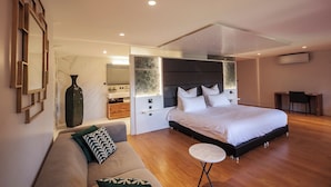 A modern bedroom with a large bed, a sofa, a small round table, and a vanity with a mirror. - Chateau de Roquefoulet (Montgeard)