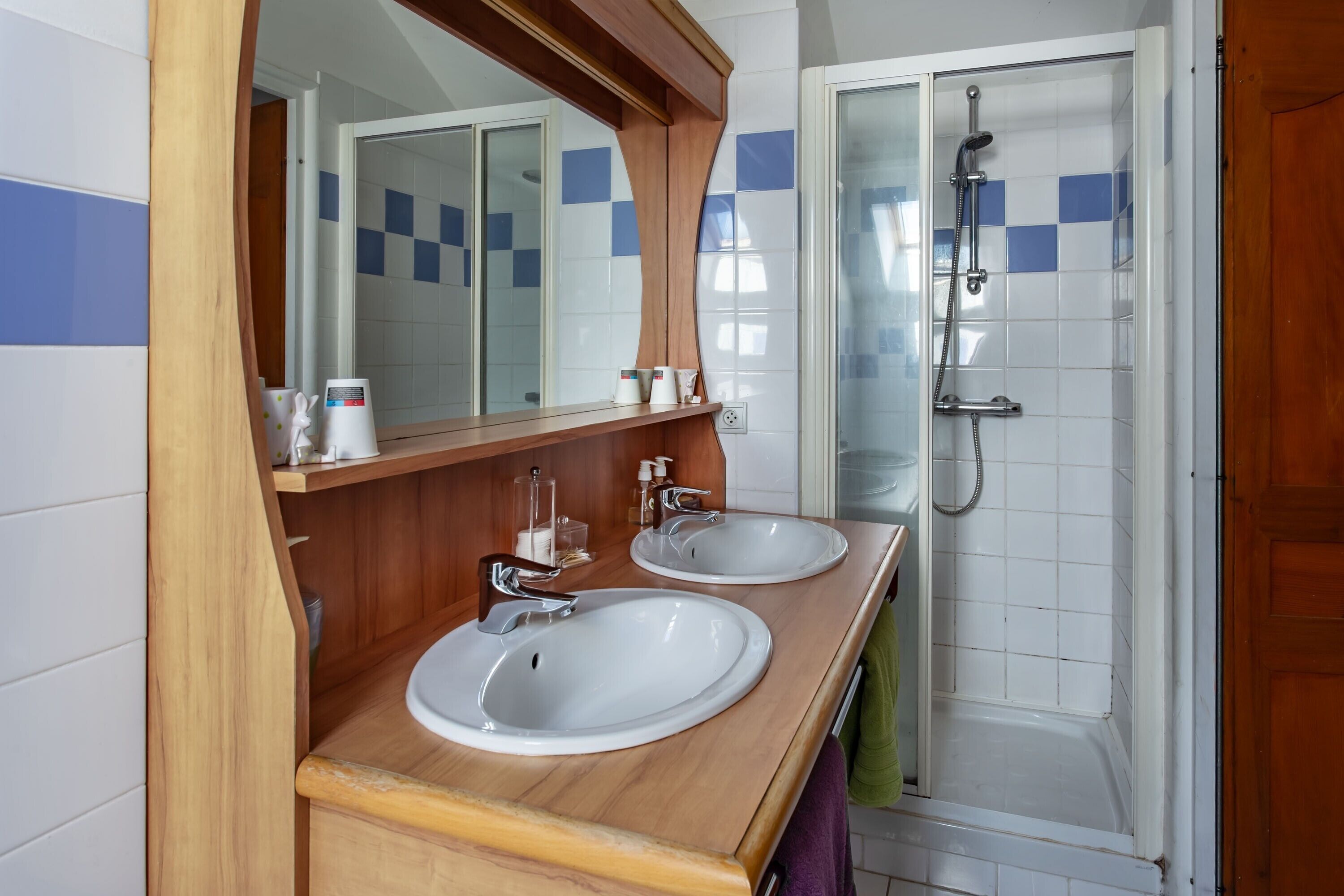 Ein Badezimmer mit zwei Waschbecken, einer Dusche und einem Spiegel.