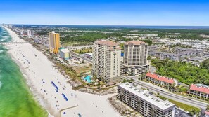 A coastal resort with beachfront hotels, a swimming pool, and a bridge connecting to the mainland. - Grand Panama PCB 2BR Beach Views 2 Pools Sleeps 8 (Panama City Beach)