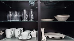 A glass display case with various glassware and white ceramic dishes. - Malila Apartaments Cracow Center Dunin 3 (Kraków)