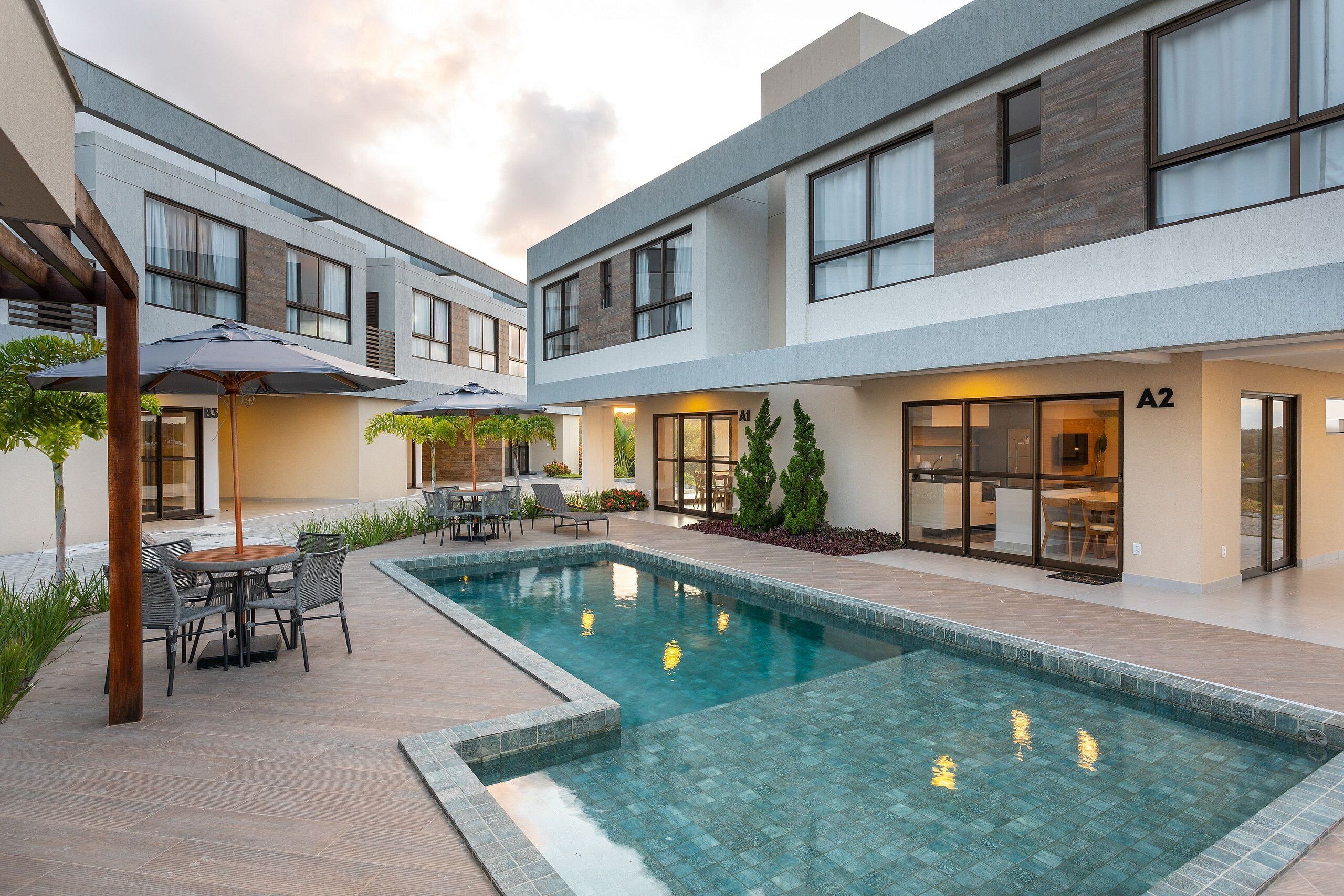 A modern building with a pool, outdoor seating, and a restaurant.