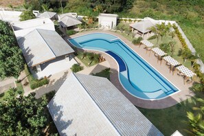 Un resort con una amplia piscina, varias habitaciones para huéspedes y zonas de estar al aire libre.