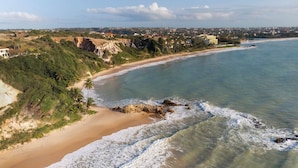 Eine Küstenlandschaft mit Strand, Klippen und einer entfernten Stadtansicht.