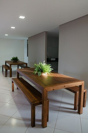 A modern dining area with a wooden table and benches, a potted plant, and recessed ceiling lighting.