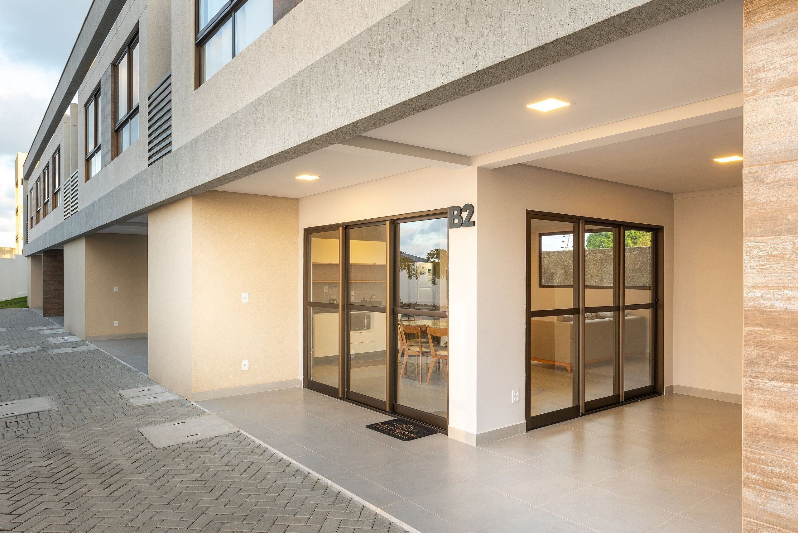 A modern building with a covered entrance, large glass doors, and a tiled floor.