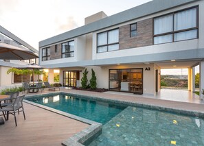 A modern building with a swimming pool, outdoor seating, and a view of the landscape. - Tabatinga Sea #B2 - Elegance by Carpediem (Conde)
