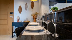 A dining area with a black countertop, white plates, and wine glasses arranged for a meal. - Enseada de Coqueirinho #201 - Apt by Carpediem (João Pessoa)