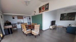 A modern living space with a dining area, kitchen, and seating area. - Modern Creole house with swimming pool, garden and sea view (Etang Salé les Hauts) (L'Étang-Salé)