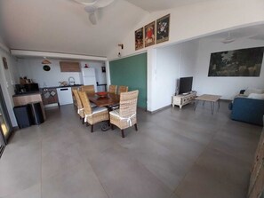 A modern living space with a dining area, kitchen, and seating area. - Modern Creole house with swimming pool, garden and sea view (Etang Salé les Hauts) (L'Étang-Salé)