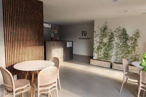 Ein moderner Empfangsbereich mit einer Rezeption, einem runden Tisch mit Stühlen und Bambuspflanzen im Hintergrund.