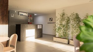 Ett välkomstområde med en receptionsdisk i marmor, en stor bambuväxt i en kruka och en skylt för Nordeste Inc.