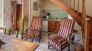 Un coin repas avec des chaises et une table en bois, une cuisine équipée d’un four à micro-ondes et d’une cuisinière, et un escalier avec des rampes en bois.