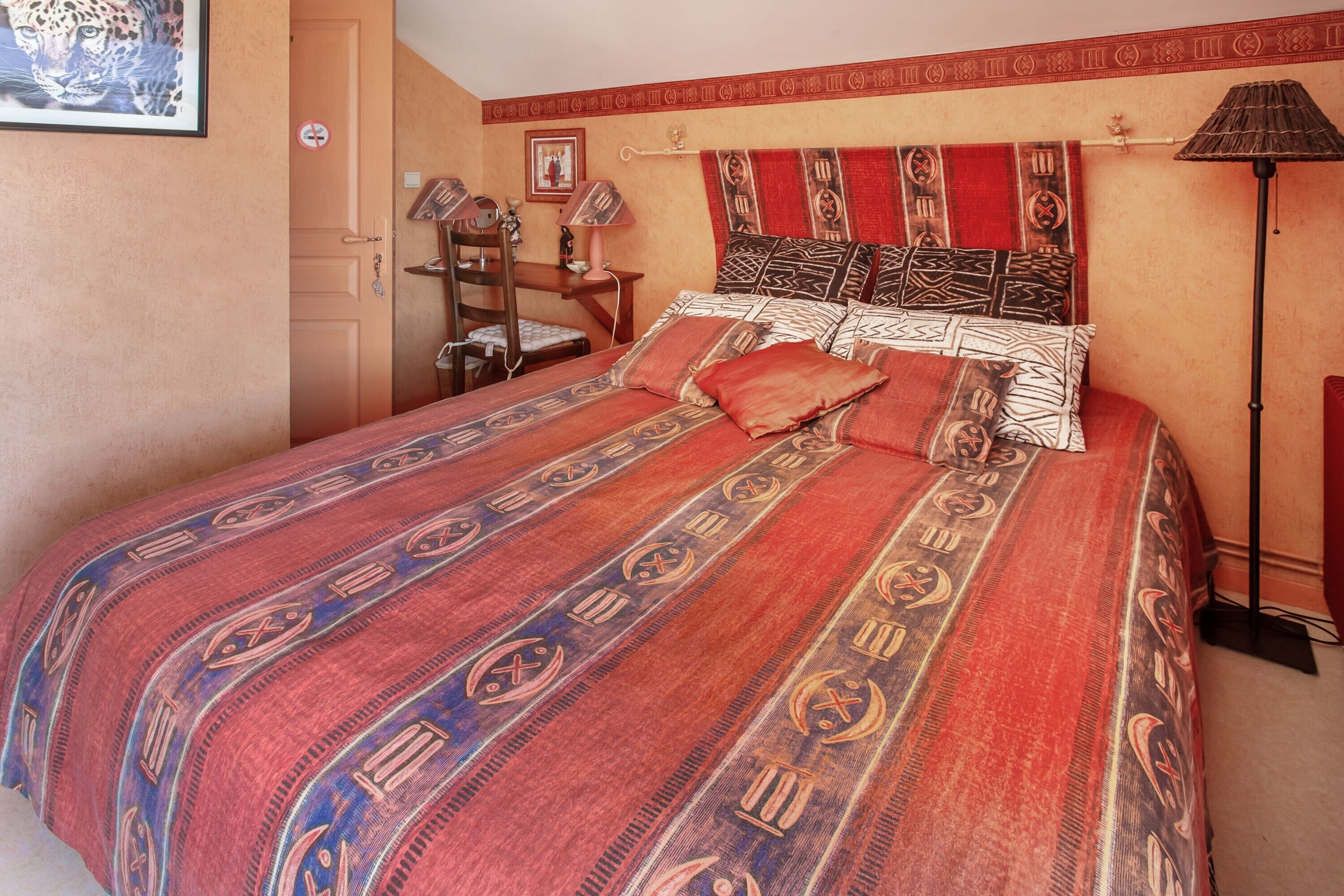 Una camera da letto con un letto, una scrivania, una sedia e una lampada.