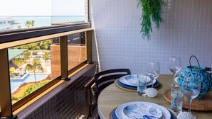Ein Esstisch mit Tellern, Gläsern und einer dekorativen Vase, mit Blick auf einen Pool und Grünflächen.