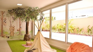 A room with a large window, a green artificial turf, a beige tent, and a bean bag chair. - Puerto Ventura #203 - Ape Ao Mar por Carpediem (João Pessoa)