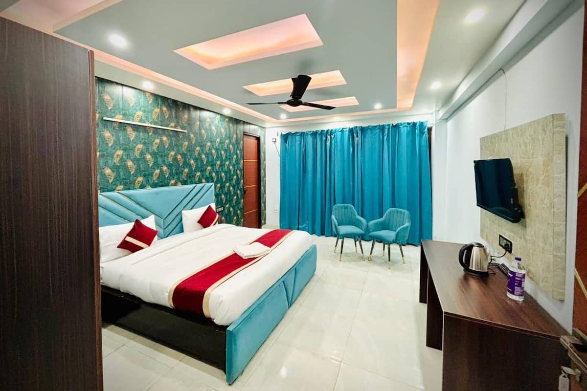 A modern hotel room with a bed, a desk, a chair, a ceiling fan, and a TV mounted on the wall.