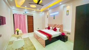 A modern bedroom with a bed, bedside table, and a desk with a chair. - The Prime Regency (Greater Noida)