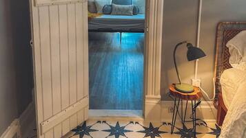 A room with a bed, a small table with a lamp, and a star-patterned floor.