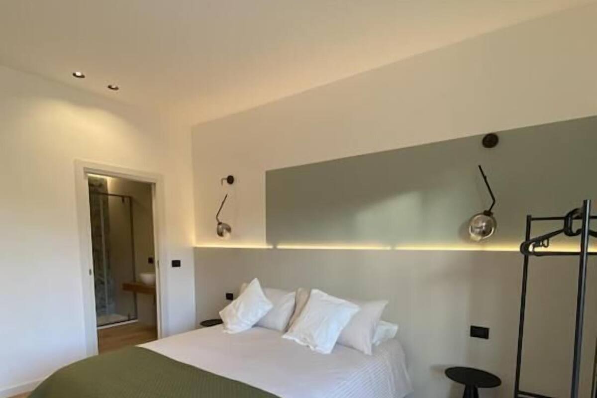 Une chambre à coucher moderne avec un grand lit, une table de chevet, une armoire et un dressing.