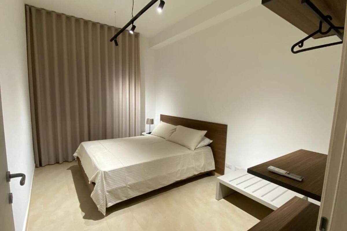 Une chambre à coucher moderne avec un lit, une table de chevet et un luminaire suspendu.