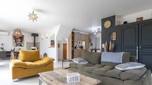 A modern living room with a sofa, coffee table, and a dining area in the background. - Charming Villa in St Rémy de Provence with Pool (Saint-Rémy-de-Provence)