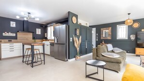 A modern kitchen with a refrigerator, bar stools, and a dining table. - Charming Villa in St Rémy de Provence with Pool (Saint-Rémy-de-Provence)