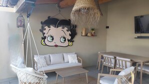 A room with a hanging chair, sofa, wooden table, TV, and a wall decoration. - Charming Villa in St Rémy de Provence with Pool (Saint-Rémy-de-Provence)