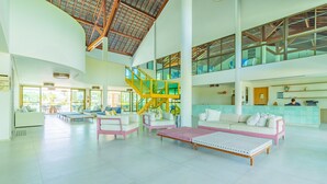 Um hall espaçoso com teto alto, escadaria central e balcão de recepção.