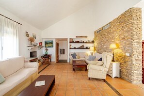 Ein Wohnzimmer mit Steinwand, einer Couch, einem Sessel, einem Couchtisch und einer Lampe.