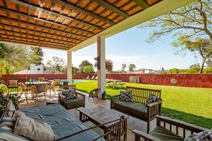 Eine Terrasse im Freien mit einem Holztisch, Stühlen und einer Couch.