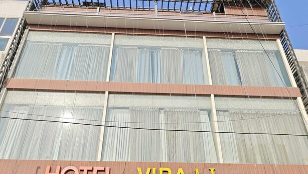 Un hôtel appelé VIRAJ Inn, doté d’une façade moderne, de grandes fenêtres et d’une entrée bien visible.