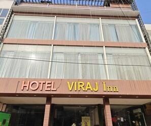 Un hôtel appelé VIRAJ Inn, doté d’une façade moderne, de grandes fenêtres et d’une entrée bien visible.