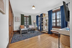 A living room with a sofa, coffee table, and a bookshelf. - 1br apt- heart of Uptown Maumee w/ fiber WiFi! #4 (Maumee)