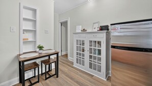 A kitchen with a white cabinet, a stainless steel refrigerator, and a wooden dining table with benches.