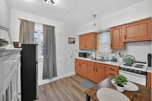 Une cuisine moderne avec des meubles en bois, un réfrigérateur noir, une cuisinière et un coin repas comprenant une table et des chaises.