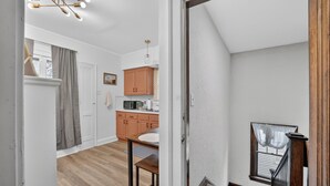 A kitchen with wooden cabinets, a dining table, and a staircase leading to an upper floor.