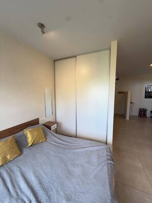 Un dormitorio con cama, mesita de noche y armario.