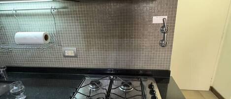 A kitchen with a stainless steel stove, a black range hood, and a tiled backsplash.