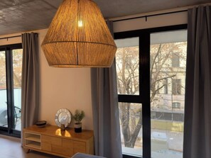Quarto moderno com uma janela grande, uma mesa consola de madeira com objetos decorativos e um pendente com textura.